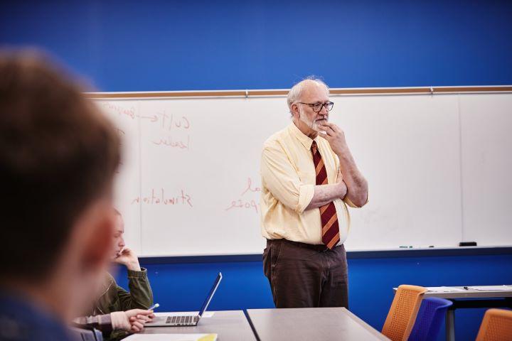 Male teacher in front of white board in classroom